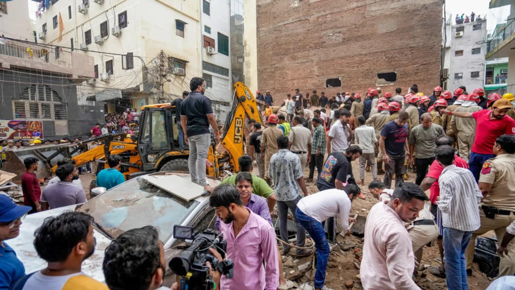 Rescue workers and residents search through rubble at the Satya Niketan building collapse site