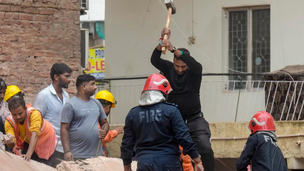 Firefighters assist with rescue work at the rubble of a collapsed PG building in Satya Niketan